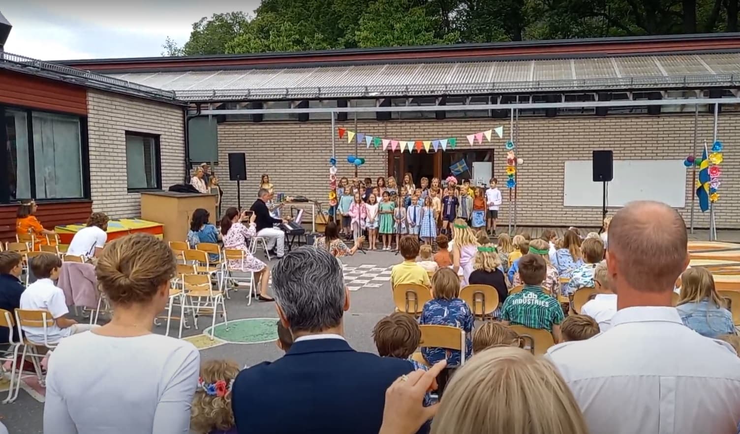 Avslutningssång på Saltängens skola. Vi ser ryggtavlorna på bl.a. en f.d. energiminister.